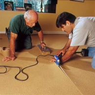 two men and women utilizing an electric seaming metal to show how-to install carpet