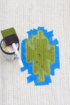 action 3 utilizing a foam brush to paint a kilim design onto a tiny cotton rug